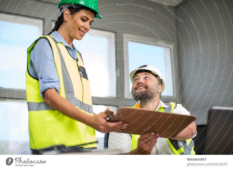 Male and female quarry staff having a meeting in site office colleagues worker blue collar worker workers blue-collar worker gravel pit clipboard clipboards