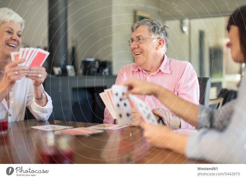 Senior couple playing cards with daughter at home daughters senior men senior man elder man elder men senior citizen twosomes partnership couples family