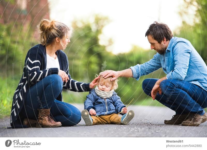 Parents stroking cute little boy on field path baby infants nurselings babies parents people persons human being humans human beings family families 35-40 years