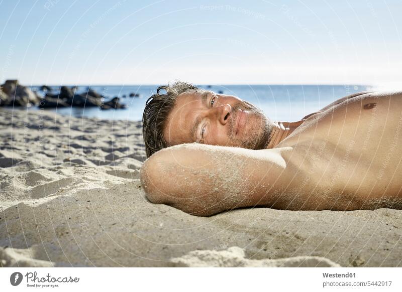 Portrait of man relaxing on sandy beach Sea ocean beaches men males water Adults grown-ups grownups adult people persons human being humans human beings