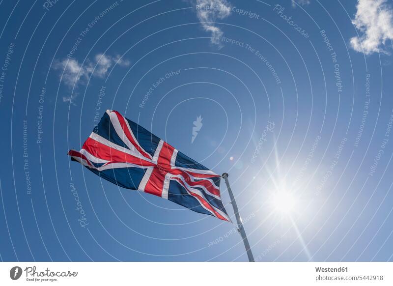 Union Jack in blue sky with backlight cloud clouds blue skies clear sky sunshine Sunny Day sunny nationality copy space British Flag light beam light beams ray