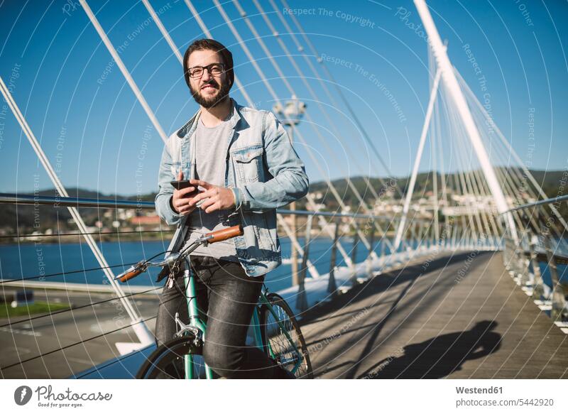 Smiling young man with fixie bike on a bridge bicycle bikes bicycles smiling smile men males transportation Adults grown-ups grownups adult people persons