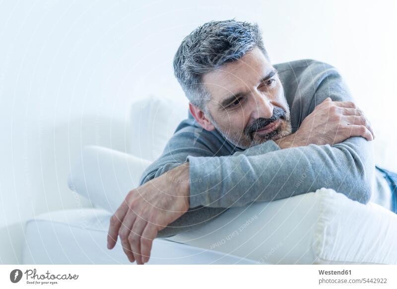 Relaxed mature man at home lying on couch settee sofa sofas couches settees men males laying down lie lying down relaxed relaxation Adults grown-ups grownups