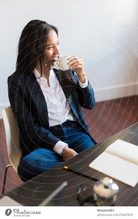 Smiling businesswoman drinking coffee during a meeting in office offices office room office rooms workplace work place place of work businesswomen