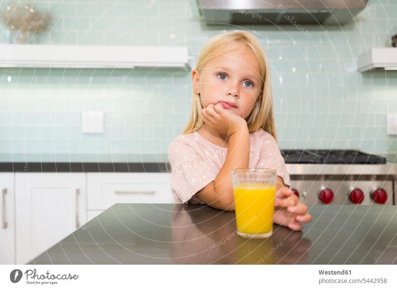 Portrait of pensive girl in kitchen with glass of orange juice portrait portraits thoughtful Reflective contemplative Juice Juices Orange Juice domestic kitchen