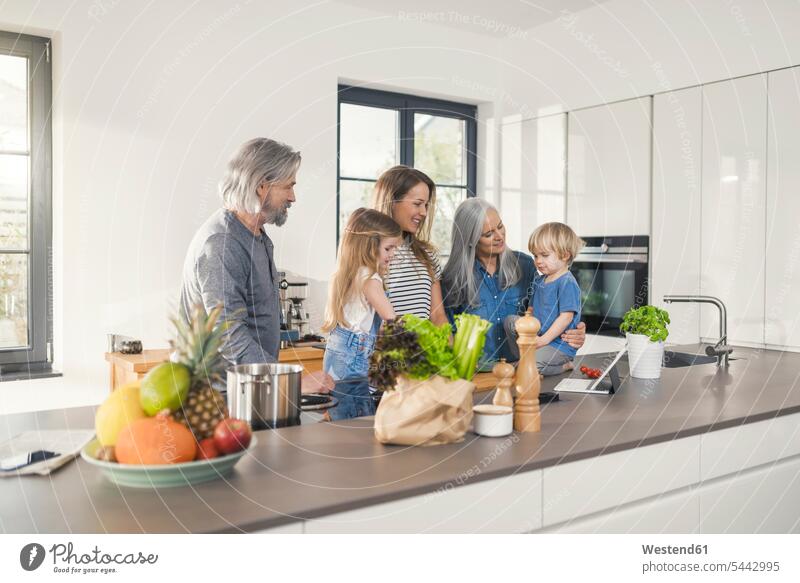Grandparents with grandchildren and their mother standing in kitchen domestic kitchen kitchens together happiness happy family families cooking recipe recipes