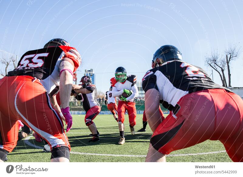 American football player running with the ball during a match helmet helmets Protective Headwear Football sport sports sports field sports fields training