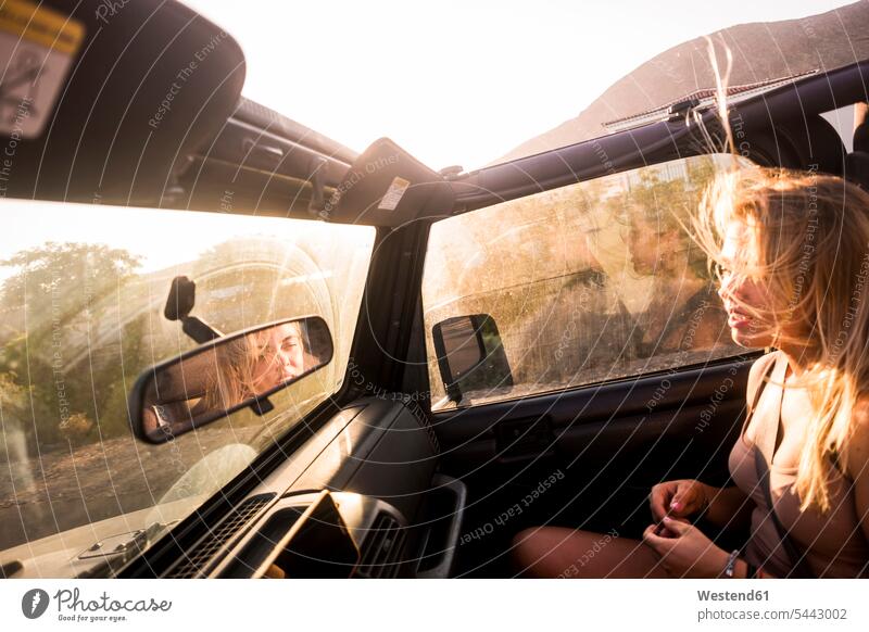 Blond woman with blowing hair sitting in car at sunset females women sunsets sundown blond blond hair blonde hair Seated automobile Auto cars motorcars