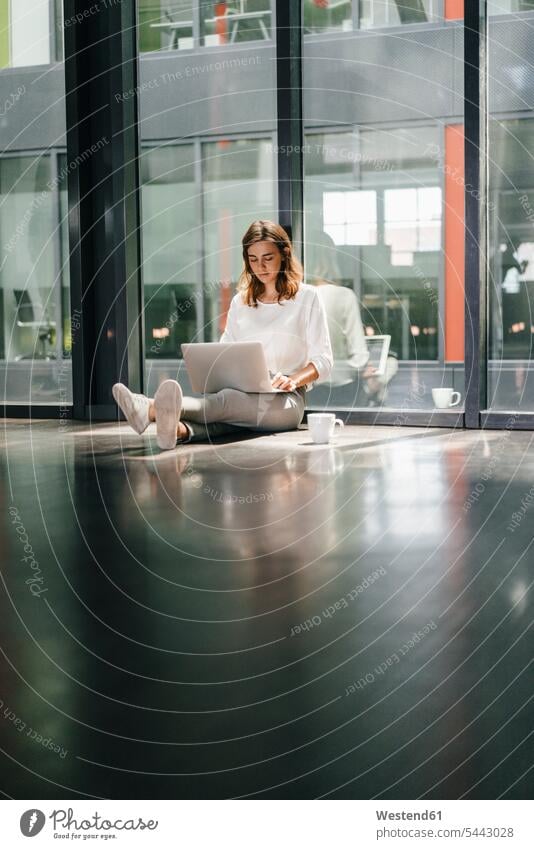 Businesswoman sitting on ground in empty office, using laptop alone solitary solo businesswoman businesswomen business woman business women Sitting On The Floor