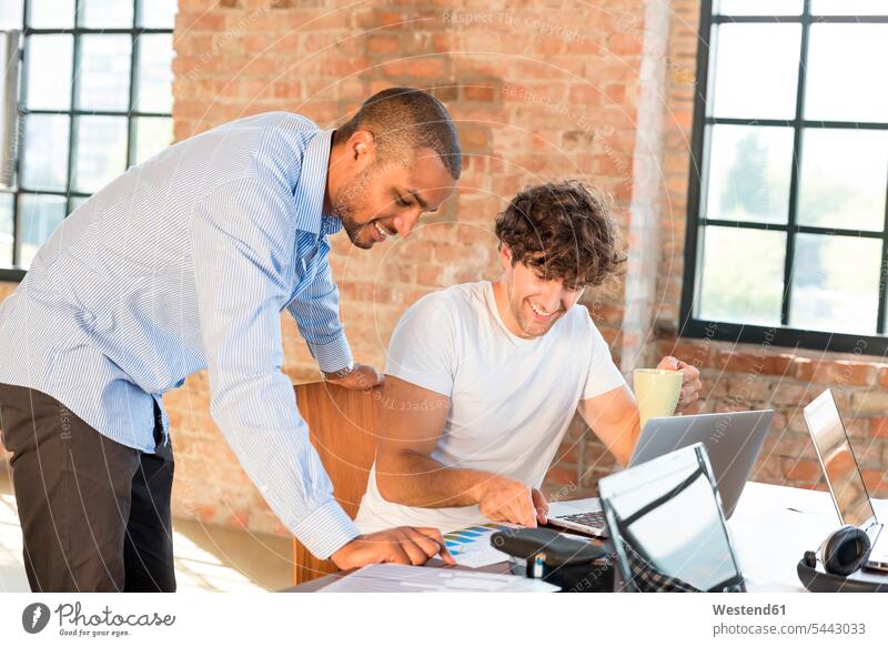 Two young businessmen working together in co-working space, using laptops Planning planning planned discussing discussion Coworking space shared workspace