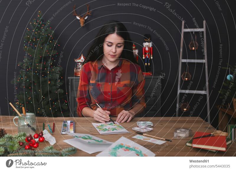 Young woman painting Christmas card with water colors females women Christmas cards Adults grown-ups grownups adult people persons human being humans