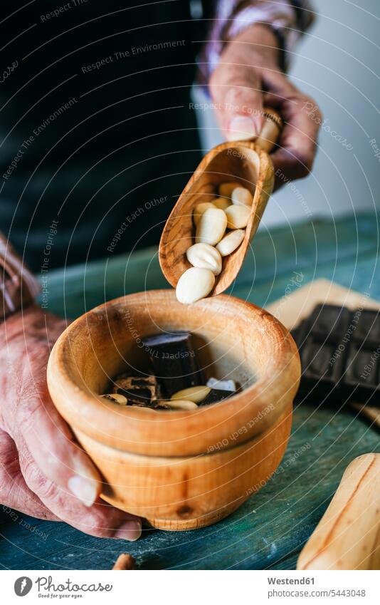 Man's hands pouring almonds in a wooden bowl wood bowl wood bowls wooden bowls Almond Almonds man men males human hand human hands Bowl Bowls Nut Nuts Food
