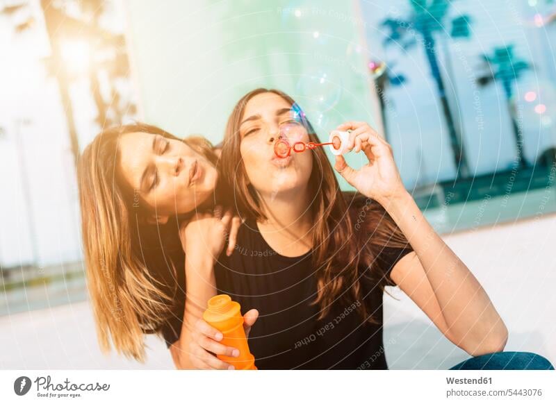 Two happy young women blowing soap bubbles Fun having fun funny female friends mate friendship woman females Adults grown-ups grownups adult people persons
