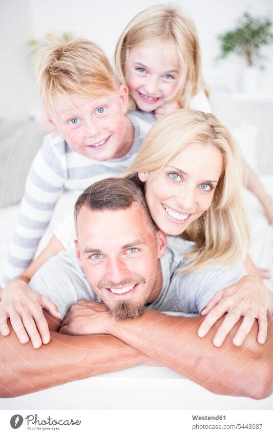 Portrait of smiling family lying in bed on top of each other laying down lie lying down relaxed relaxation portrait portraits smile families beds relaxing