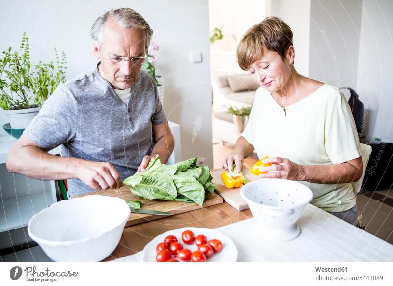 Senior couple in kitchen preparing salad together lettuce Salad twosomes partnership couples Vegetable Vegetables Food foods food and drink Nutrition