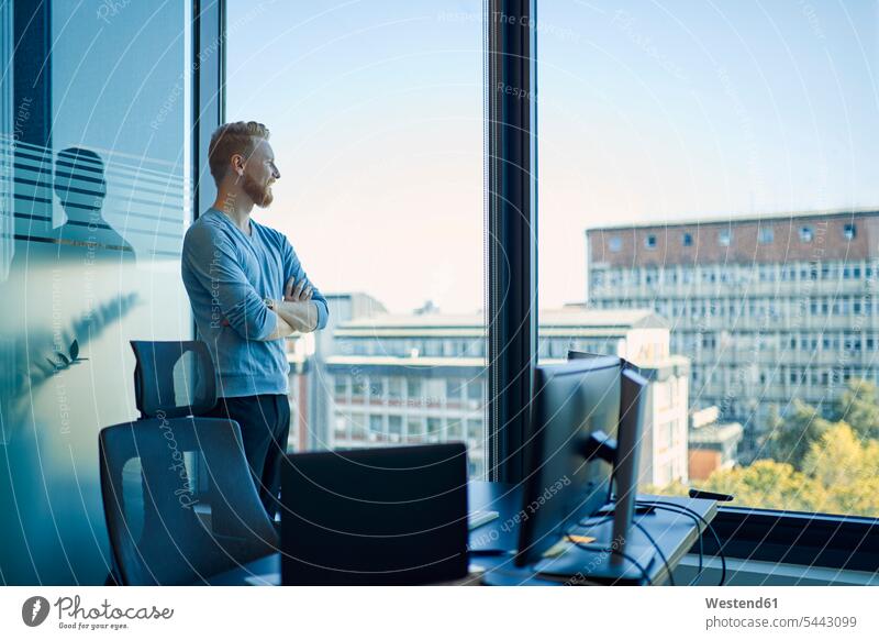 Businessman in office looking out of window offices office room office rooms Business man Businessmen Business men windows standing workplace work place