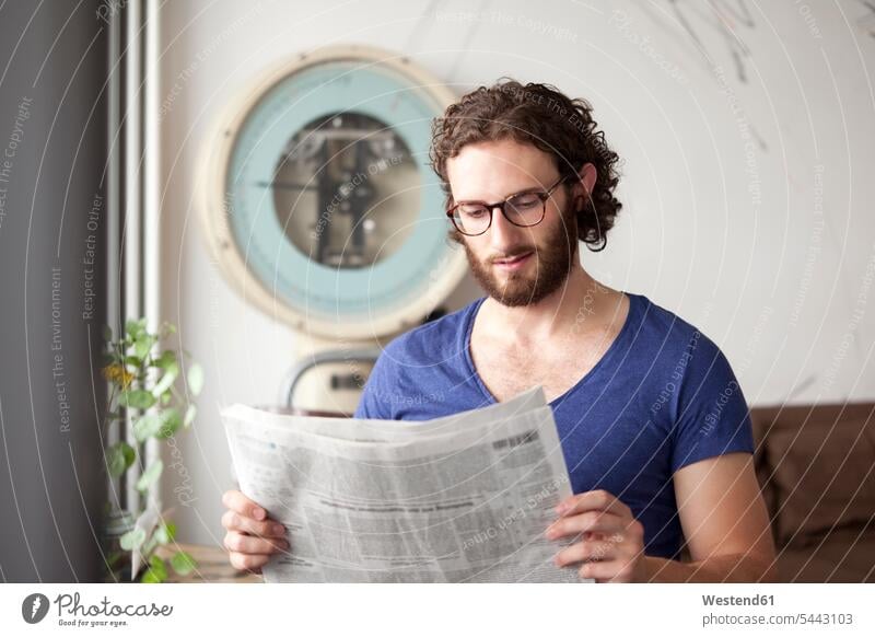 Portrait of young man reading newspaper in a coffee shop portrait portraits newspapers men males Adults grown-ups grownups adult people persons human being