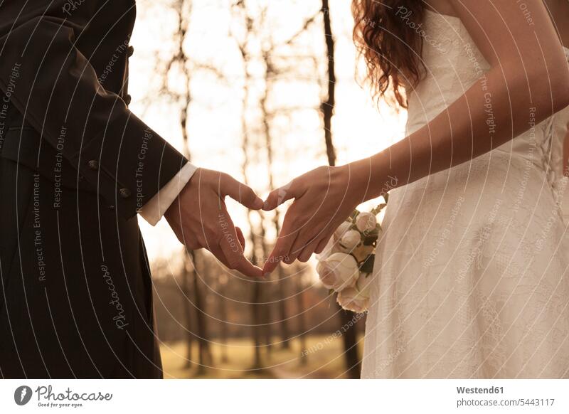Newly wed bridal couple touching hands, making heart shaped finger frame heart-shape love heart loveheart hearts park parks Finger Frame bridal couples marrying