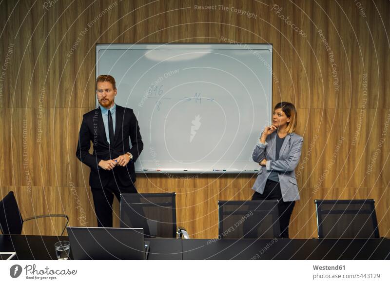 Businessman and businesswoman leading a presentation in boardroom office offices office room office rooms talking speaking Business Meeting business conference