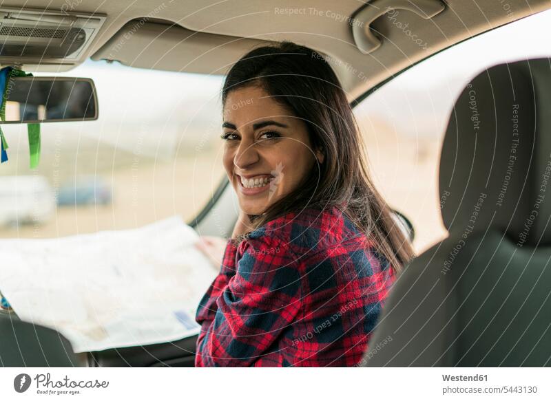 Portrait of laughing young woman with map in a car females women automobile Auto cars motorcars Automobiles Adults grown-ups grownups adult people persons