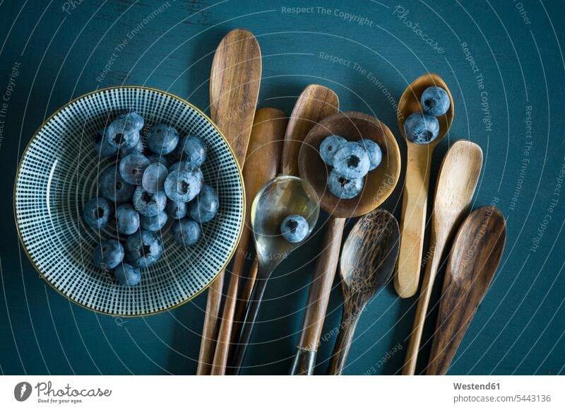 Bowl of blueberries and different spoons on blue ground still life still-lifes still lifes nobody Part Of partial view cropped Fruit Fruits Bowls close-up
