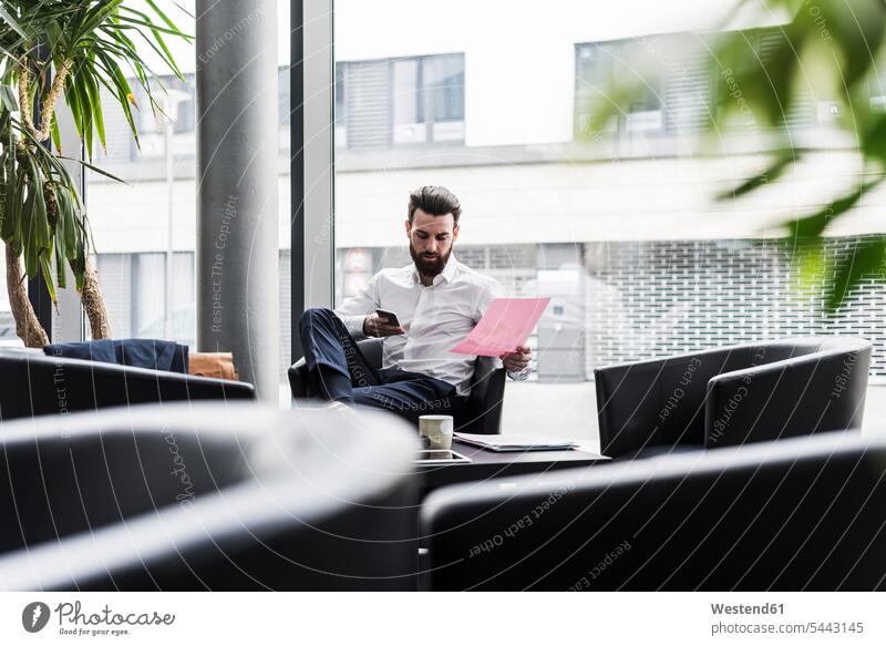 Businessman sitting in lobby, drinking coffee, reading documents caucasian caucasian ethnicity caucasian appearance european Concentration concentrating