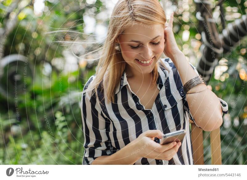 Happy blond woman looking at her smartphone businesswoman businesswomen business woman business women Smartphone iPhone Smartphones business people