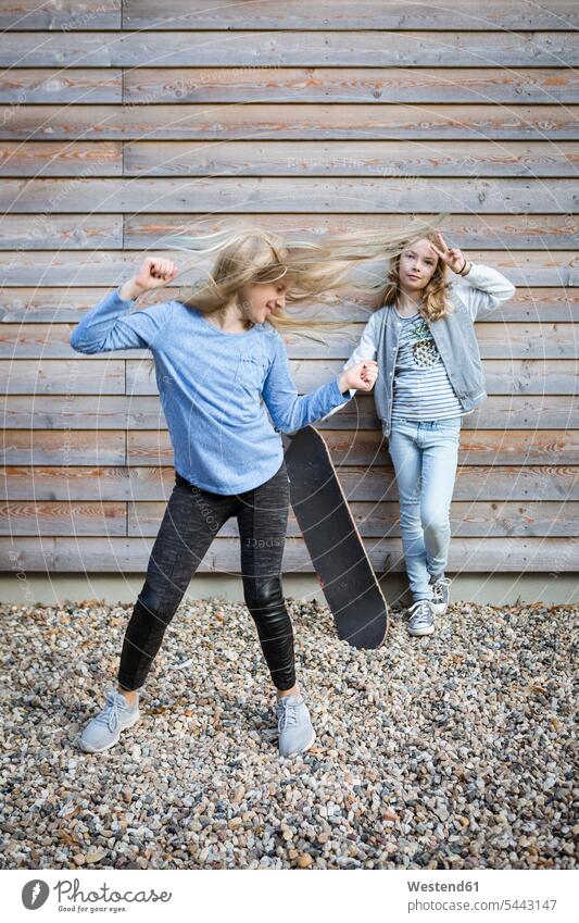 Two girls with skateboard in front of wooden facade house front females Skate Board skateboards Facade Facades child children kid kids people persons