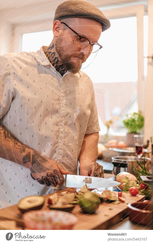 Tattooed man preparing food in the kitchen cooking chopping men males Adults grown-ups grownups adult people persons human being humans human beings