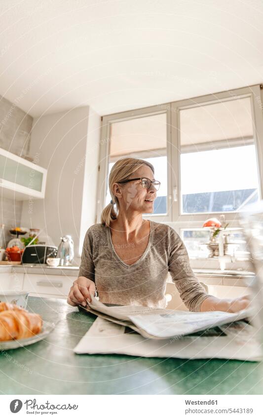 Woman at home sitting at table with newspaper newspapers woman females women Adults grown-ups grownups adult people persons human being humans human beings