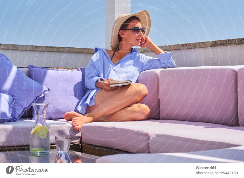Woman with book relaxing on sun deck Glass Drinking Glasses woman females women Water vacation Holidays relaxation books Adults grown-ups grownups adult people