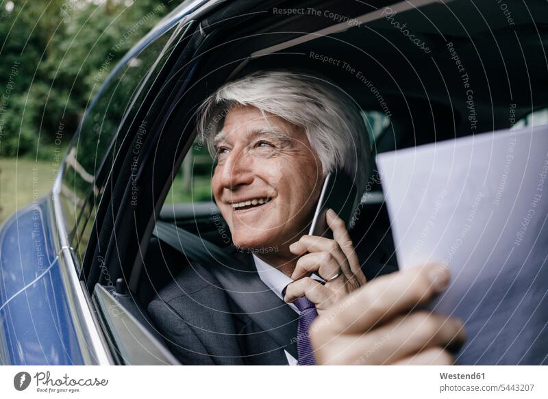 Smiling senior businessman with documents on the phone in a car call telephoning On The Telephone calling Businessman Business man Businessmen Business men