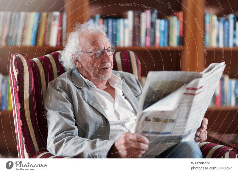Senior man sitting in library, reading newpaper Seated armchair Arm Chairs armchairs retirement home nursing home newspaper newspapers senior men senior man