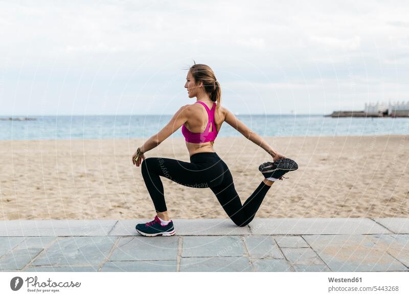 Young woman stretching and warming up for training at the beach exercising exercise practising beaches females women warm up Adults grown-ups grownups adult