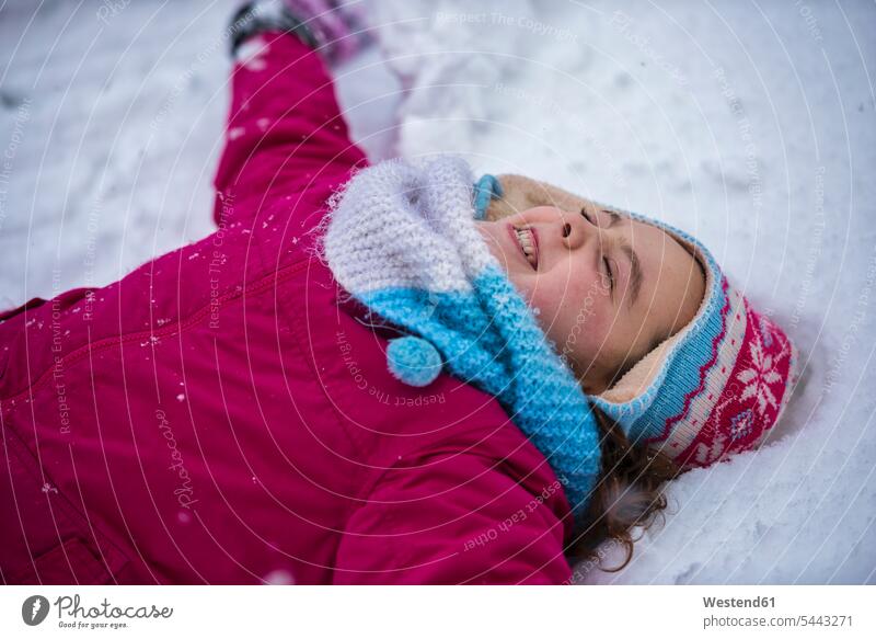 Smiling girl making a snow angel females girls lying laying down lie lying down child children kid kids people persons human being humans human beings portrait