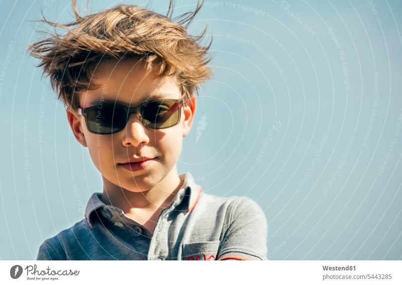 Portrait of cool boy with sunglasses and blowing hair in front of sky boys males sun glasses Pair Of Sunglasses portrait portraits child children kid kids