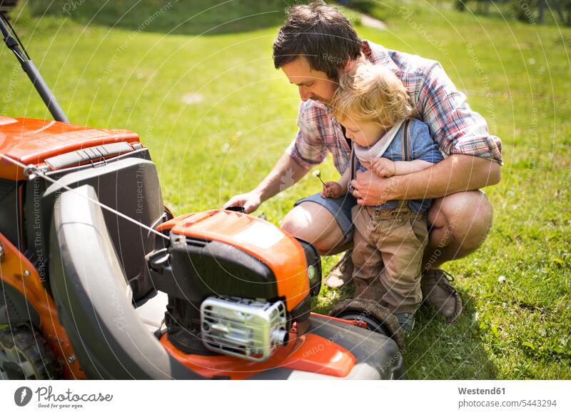 Father with his little son and lawn mower garden gardens domestic garden father pa fathers daddy dads papa lawnmower sons manchild manchildren parents family