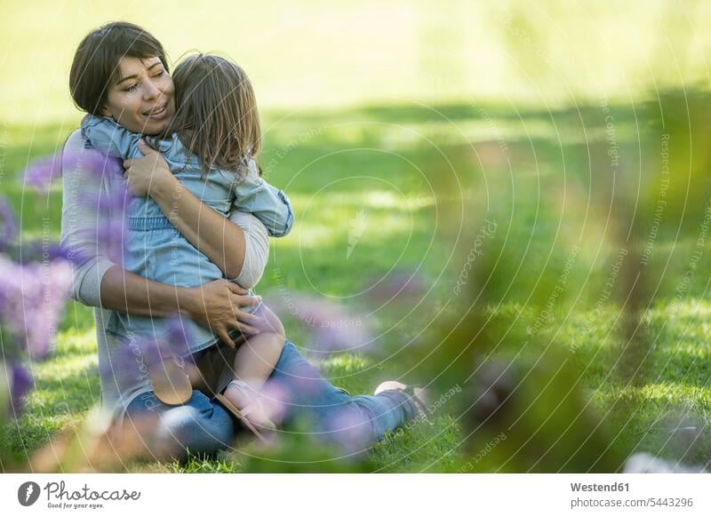 Mother hugging daughter in garden gardens domestic garden daughters smiling smile mother mommy mothers ma mummy mama embracing embrace Embracement happiness