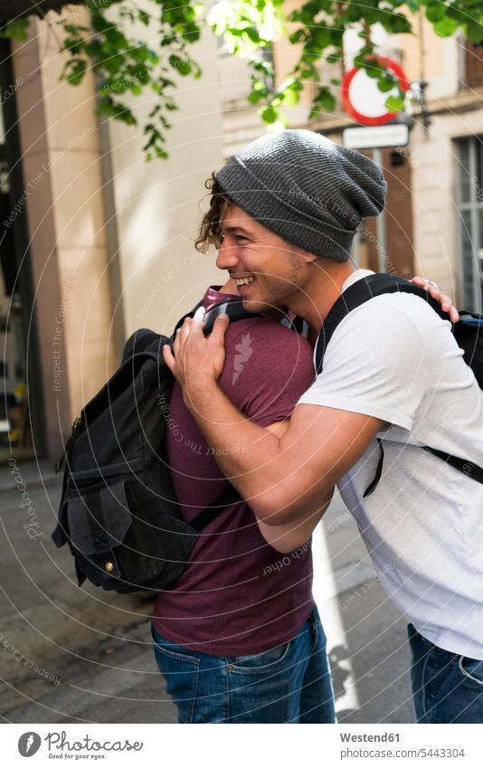 Two young men embracing in the city friends embrace Embracement hug hugging smiling smile happiness happy friendship town cities towns outdoors outdoor shots