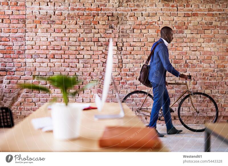 Businessman pushing bicycle in office Business man Businessmen Business men bikes bicycles business people businesspeople business world business life