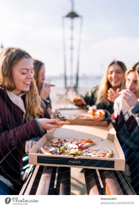 Four friends eating pizza outdoors mate female friend Alimentation food Food and Drinks Nutrition foods Pizza Pizzas smile share human human being human beings