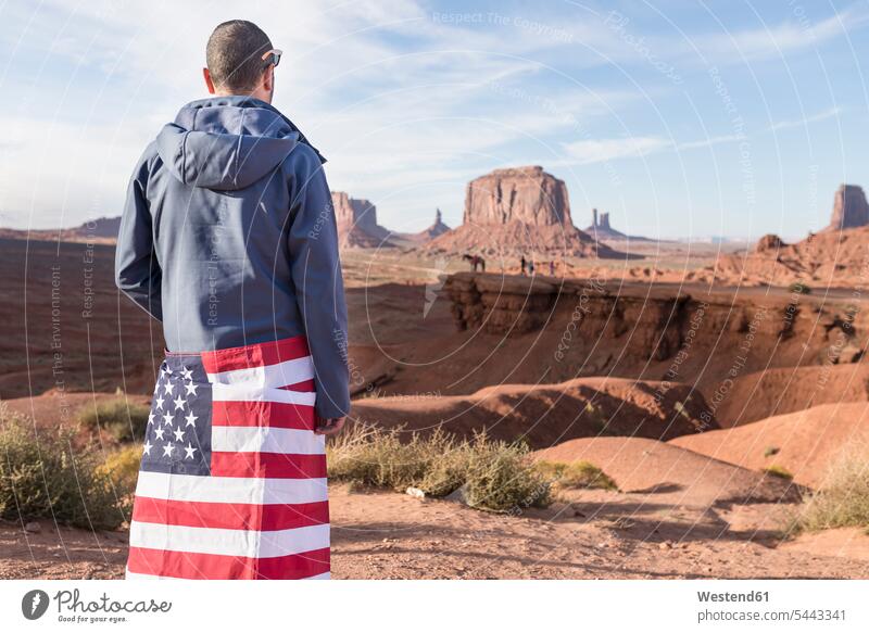 USA, Utah, back view of young man with American flag at Monument Valley ensign national flags ensigns males banner banners Adults grown-ups grownups adult