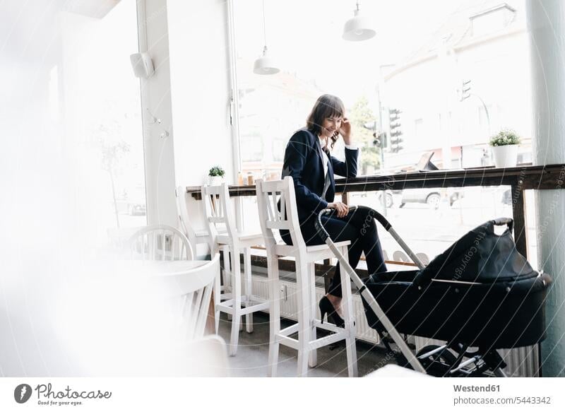 Businesswoman working from cafe with pram on her side sitting Seated businesswoman businesswomen business woman business women At Work mother mommy mothers