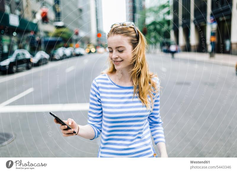 USA, New York, Manhattan, Young woman walking in the street, holding mobile phone mobiles mobile phones Cellphone cell phone cell phones message checking