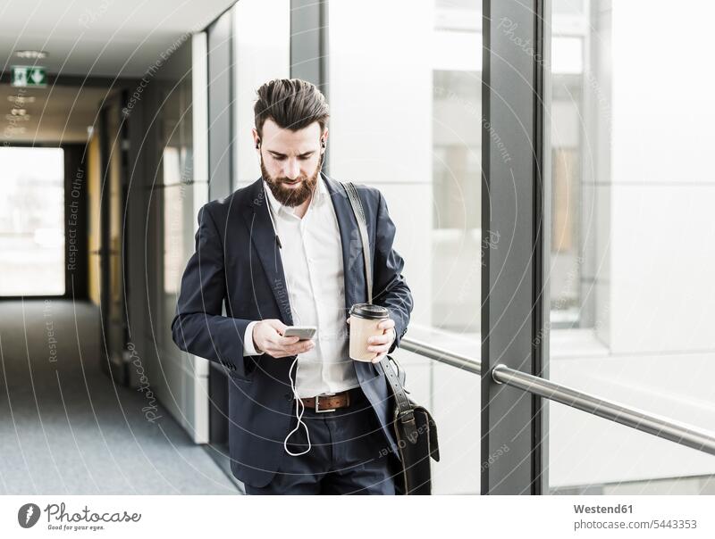 Businessman walking in office building while talking on the phone with ear phones headphones headset call telephoning On The Telephone calling Smartphone iPhone