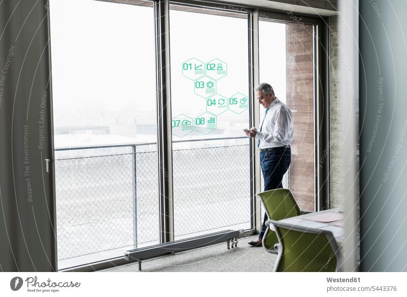 Businessman standing at windowpane with data in office Business man Businessmen Business men business people businesspeople business world business life offices