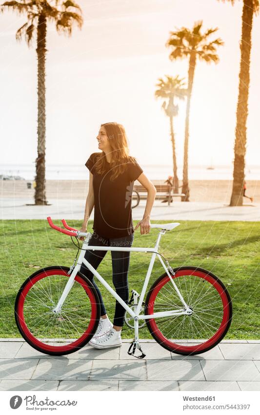 Smiling young woman with fixie bike bicycle bikes bicycles females women transportation Adults grown-ups grownups adult people persons human being humans