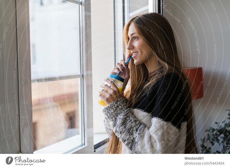 Young woman at the window drinking homemade drink females women smiling smile windows Adults grown-ups grownups adult people persons human being humans