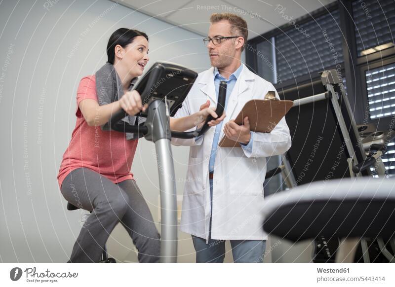 Doctor talking to patient on exercise machine fit practice doctor physicians doctors exercise machines stationary bike Stationary Bikes patients illness disease