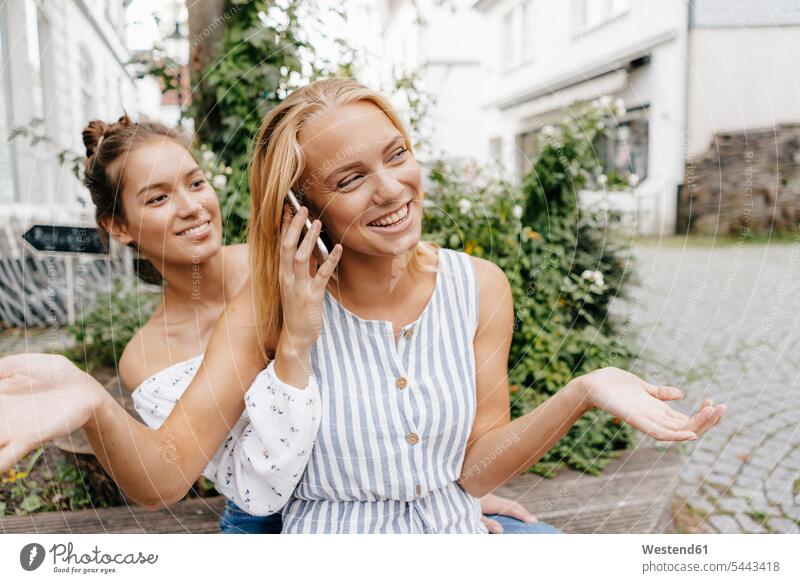 Two happy young women with cell phone in the city female friends mobile phone mobiles mobile phones Cellphone cell phones town cities towns happiness woman
